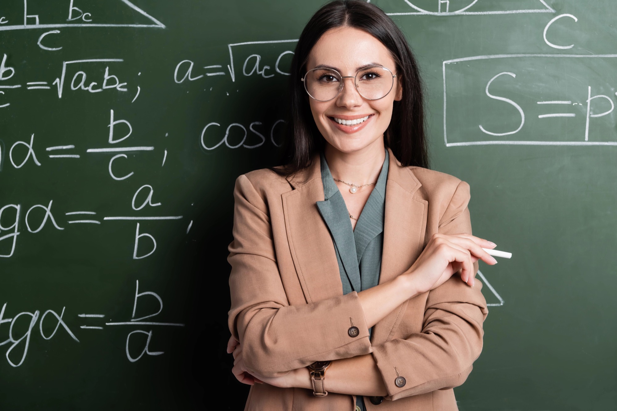Smiling teacher in front of a chalkboard with math formulas